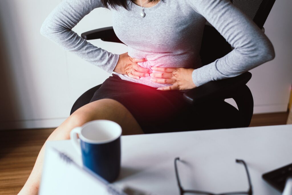 Woman having painful stomach ache during working from home